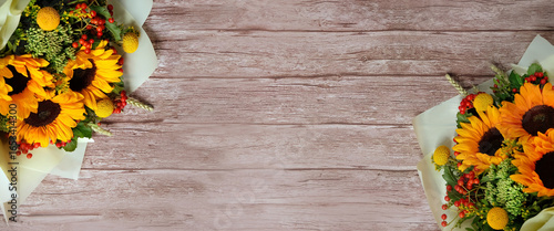 autumn background with bouquets of sunflowers on rustic wooden background. seasonal floristic composition. symbol of indian summer, august, end of summer, cozy autumn. top view. copy space. banner