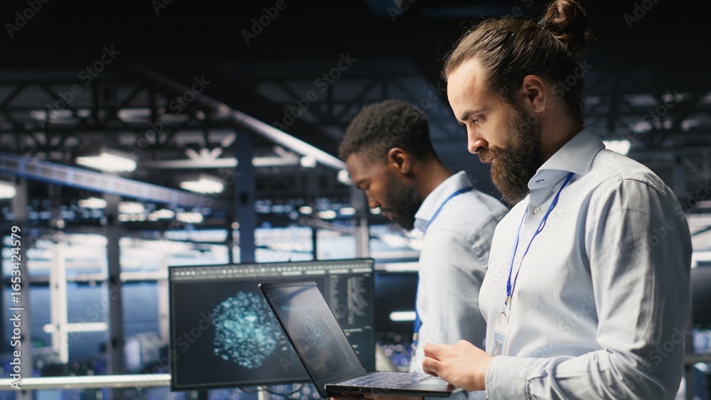Technician holding laptop walking on server farm platform, doing AI machine learning automatization. Data center programmer using notebook, doing maintenance using artificial intelligence Technician holding laptop walking on server farm platform, doing AI machine learning automatization. Data center programmer using notebook, doing maintenance using artificial intelligence