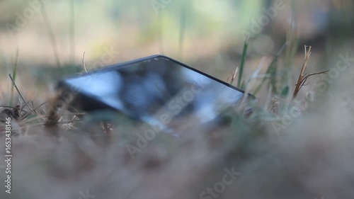 A mobile phone lying on the ground being picked up by a person. Close-up footage showing a hand lifting the smartphone from the floor. Perfect stock video for technology, accidents, lost items, or eve