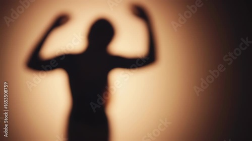 Blurry silhouette of a person with outstretched arms against a soft, muted, warm-toned background