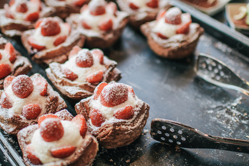 Danish pastry filled with cream, strawberries, prinking of icing sugar. Delicious homemade small cakes