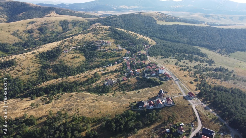 Fototapeta premium Aerial view of Zlatibor highlands village with forested hills and scattered houses in summer. g.