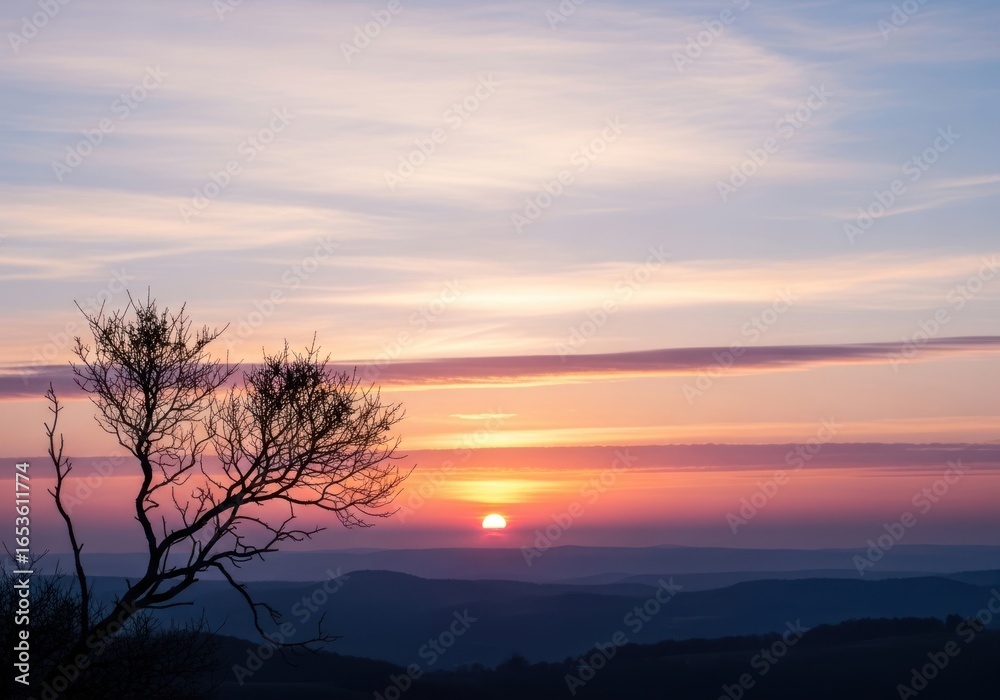 Fototapeta premium Silhouetted Tree Against Fiery Sunset Over Rolling Hills, Serene Landscape.