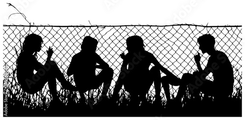 Silhouette of Four Teens Sitting Against a Fence