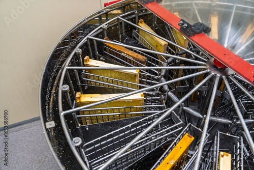 A modern honey extractor with honeycomb frames, essential for harvesting pure honey. Ideal for beekeeping, this equipment showcases the honey production process efficiently.