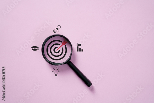 Magnifying glass focusing on target with education icons, symbolizing learning goals, knowledge, career achievement, academic success, innovation, and personal growth.