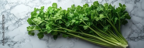 Fresh celery stalks with vibrant green leaves arranged on a white marble surface (1)