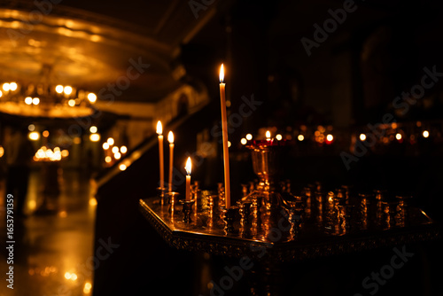 burning candles in the temple, wax candles lit against background of a cross with a crucifix, the concept of christian religion, prayers for the salvation of the soul, soft focus