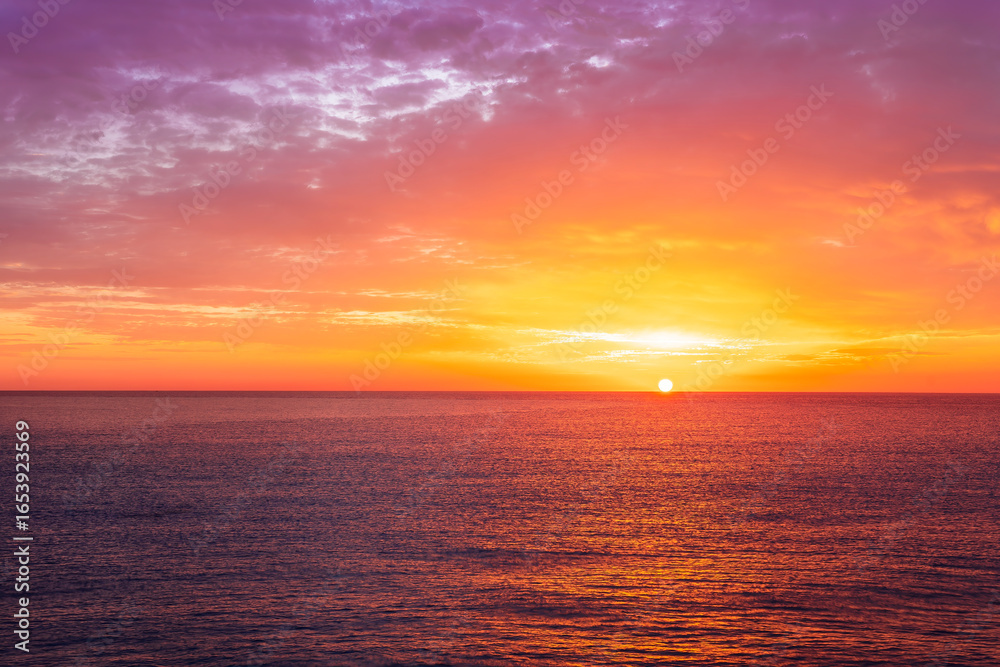 Fototapeta premium beautiful sunrise or sunset seascape with amazing calm sea water with waves and colorful amazing cloudy morning sky on background