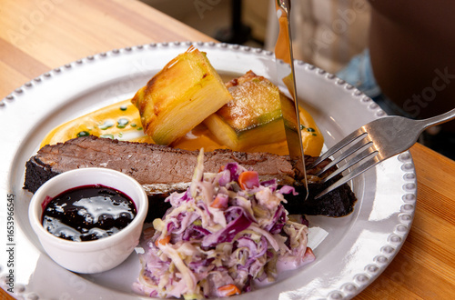 A fork and knife are used to cut a brisket.