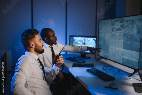 Εκτύπωση καμβά Two security guards sitting by workplace in front of monitors and observing cctv