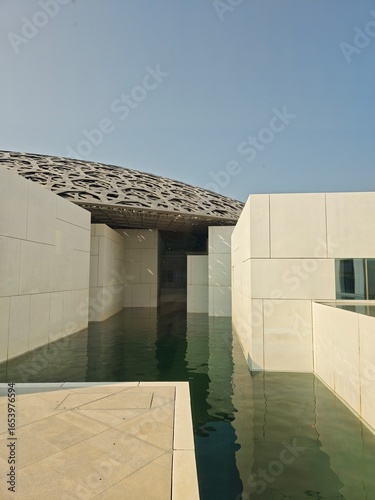 Louvre Abu Dhabi architecture with water reflection and geometric dome, modern design