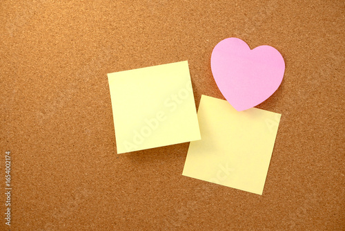 Heart shaped note and paper note on brown cork board texture background