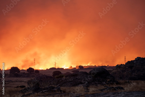 A Massive Wildfire Raging Under a Glowing Orange and Red Sky at Night.