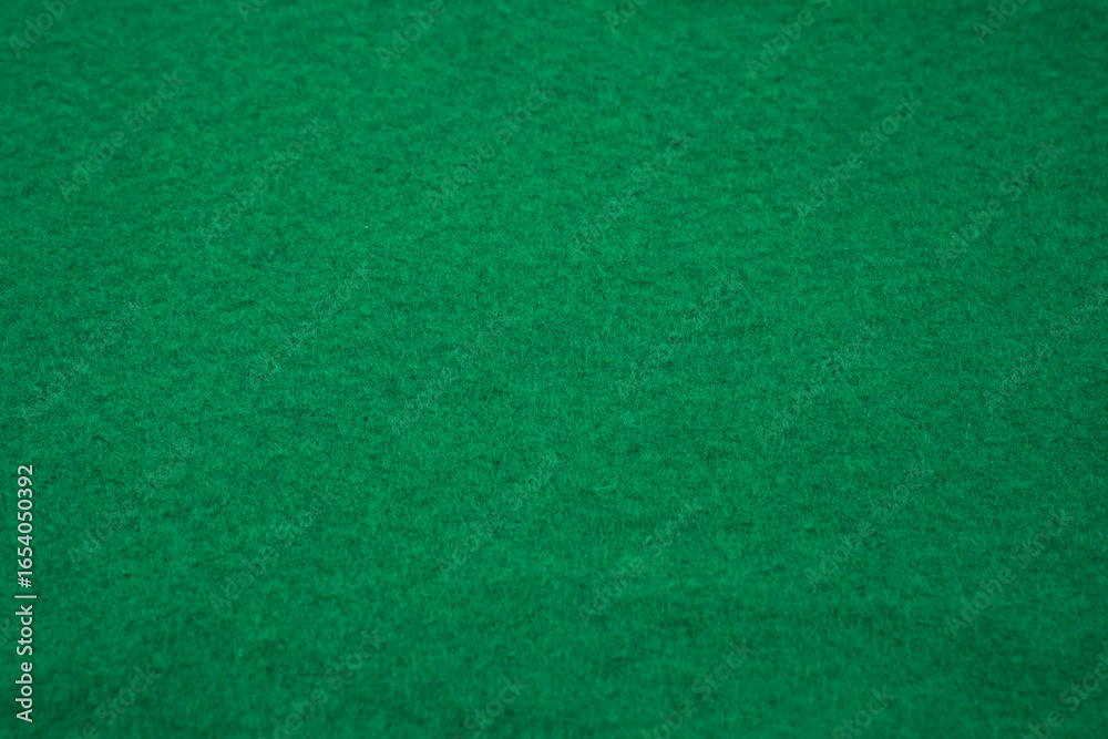 Fototapeta premium The vibrant green surface features a soft texture, perfect for board games or crafting. It creates an inviting atmosphere for various activities in an indoor space.