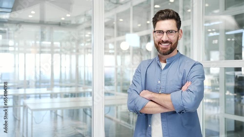 Portrait of smiling successful businessman standing with crossed arms in a business office. Confident happy manager looking at camera. Empty copy space for writing text. Template for advertising