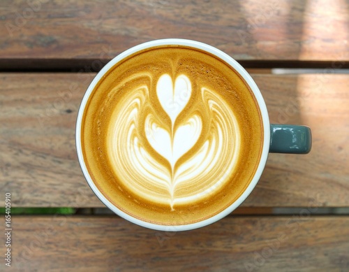 Beautiful latte art coffee served in ceramic cup on wooden table.