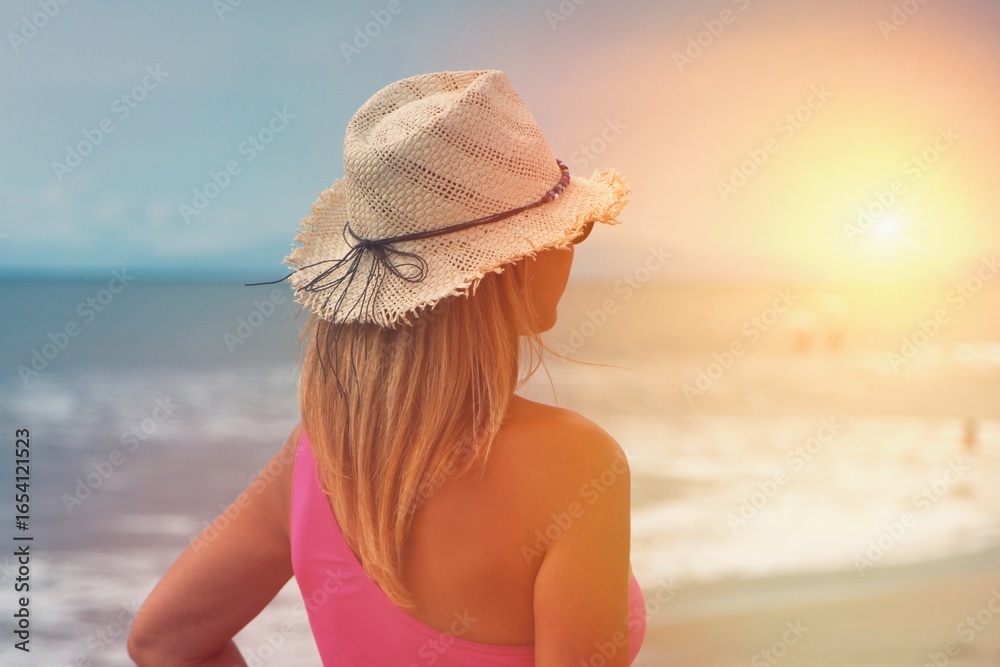 Beauty happy woman in her hat is back and admire sunset over sea Beauty happy woman in her hat is back and admire sunset over sea
