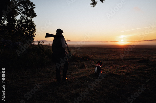 Hunter and dog in sunrise