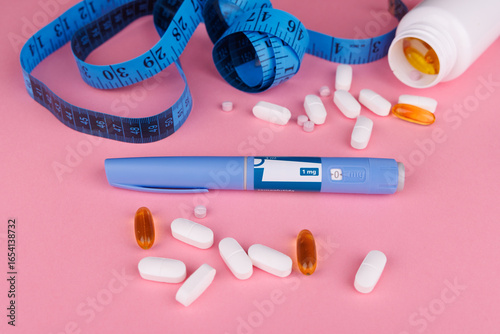 Overhead shot of semaglutide pens, blue measuring tape, and white pill jar on pink table, representing weight loss, healthy lifestyle, and telehealth.