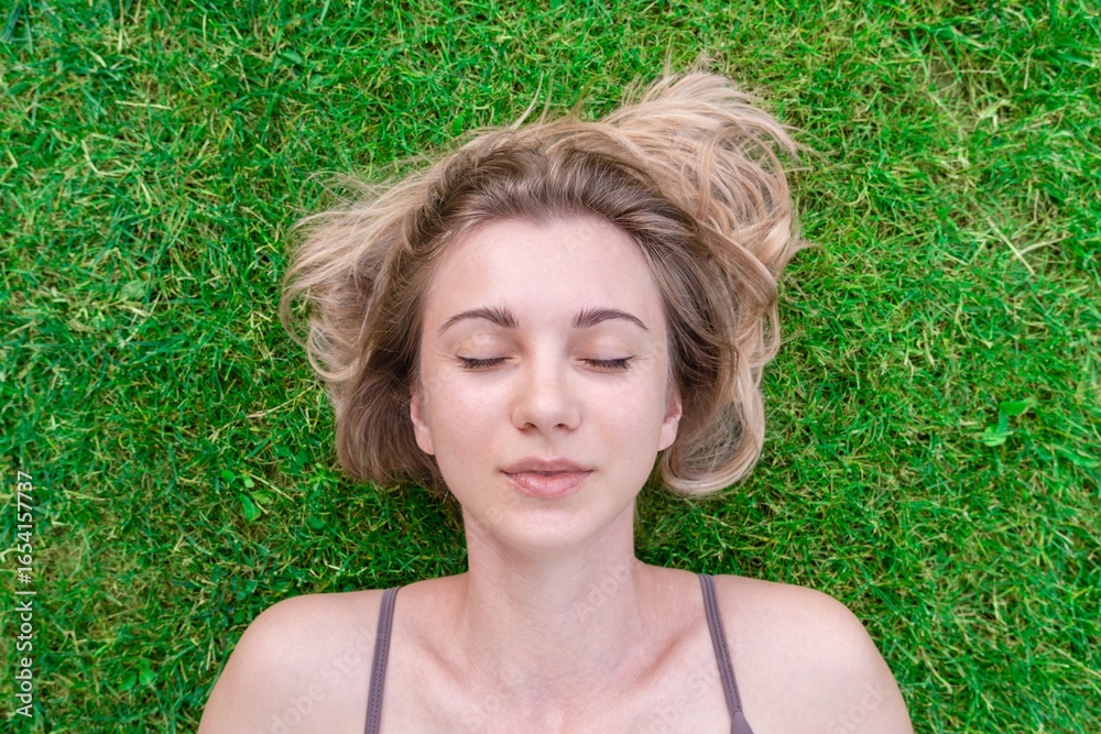Close up of beautiful young woman lying down in the green grass Close up of beautiful young woman lying down in the green grass