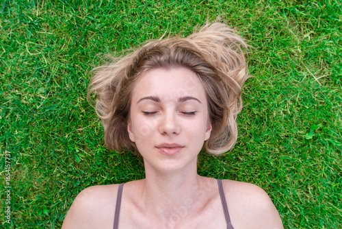 Fotografía Close up of beautiful young woman lying down in the green grass