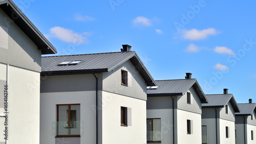 Terraced family homes in newly developed housing estate. The real estate market in the suburbs. New single family houses in a new development area. Residential homes with modern facade. 