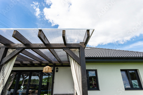 Obraz na płótnie The terrace behind the house has visible beam connections, the roof is covered with polycarbonate
