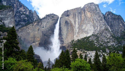 Majestic Waterfall Cascading Down Rocky Cliffs with Lush Greenery and Blue Sky