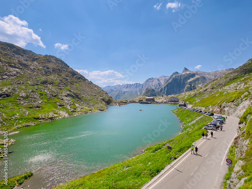 A serene alpine lake perfectly reflecting the peaks of the surrounding mountains, captured at the breathtaking summit of the historic Great St Bernard Pass on a crystal-clear summer day