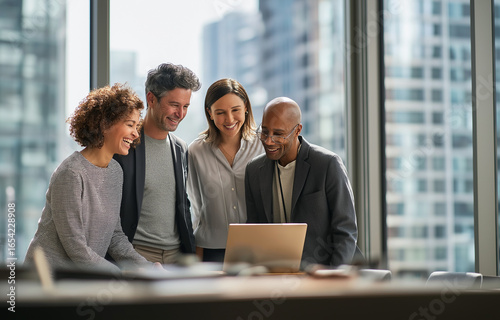 A group of business people in an office setting, gathered around a laptop