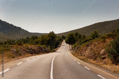 Panorama sur une route de montagne dans le sud de la France au coucher du soleil avec une ambiance lumineuse chaude, moto vue de face au loin, Marseille