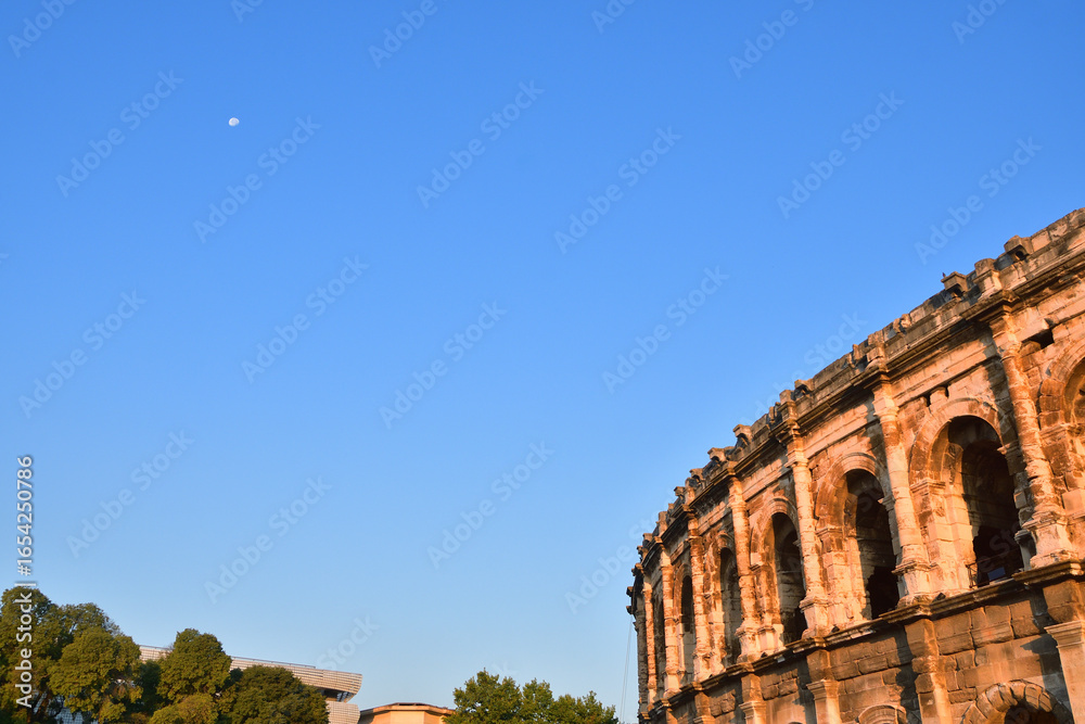 Obraz premium Early Morning View of the Nîmes Arena with the Moon — Nîmes, France, 13 August 2025