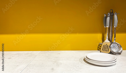 Wallpaper Mural Metallic stylish kitchen set with spatulas, skimmer, ladle, white plates and kitchen utensils on wooden surface against bright yellow wall, with space for text banner, cooking and home furnishing conc Torontodigital.ca