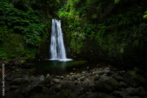 Salto do Prego, waterfall in sunset light on Sao Miguel island. Beautiful landscape with rocks, river and green trees in the jungle. Summer scene from nature, Azores Islands, Portugal