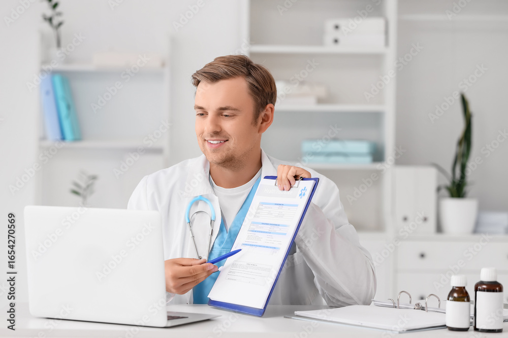 Obraz premium Male doctor with clipboard and laptop giving online consultation in clinic