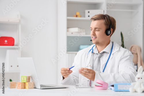 Wallpaper Mural Male pediatrician in headset with jaw model giving online consultation at hospital Torontodigital.ca