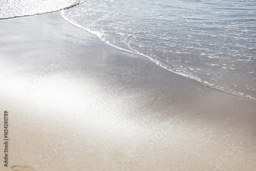 Ocean water on beach sea sand with sun reflection