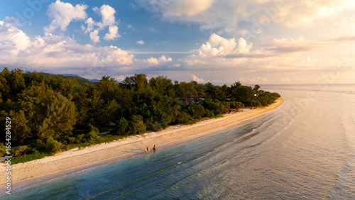Foto Two horses ride along the coastline in Gili Trawangan, Indonesia, during the sunset
