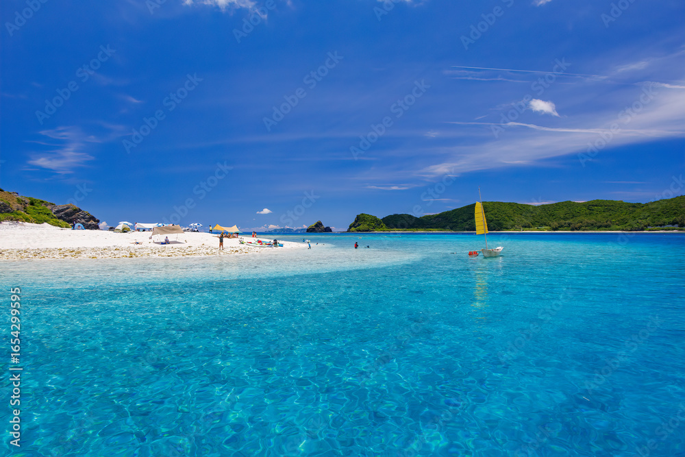 Fototapeta premium 無人島の嘉比島が見える。 白砂のビーチには観光客が上陸している。 パラソルやボート、サバニ（沖縄特有の双胴船）も見える。 船上からも水底の様子が見える。 素晴らしい透明度。 沖縄県島尻郡慶良間諸島座間味島嘉比島-2025/6/27 