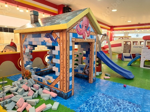 Wallpaper Mural A colorful indoor playground with a brick playhouse, blue slide, and soft foam blocks for children. Torontodigital.ca