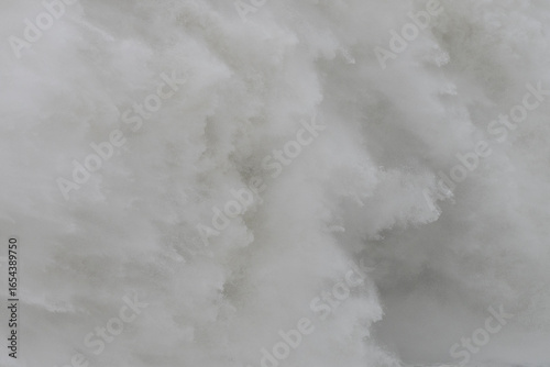 Obraz na plátně Waterfall tumbling over rocky cliff, generating misty white spray against dark s