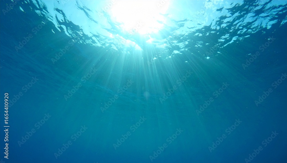 Obraz premium Sunlight beams penetrate deep blue ocean surface creating serene view