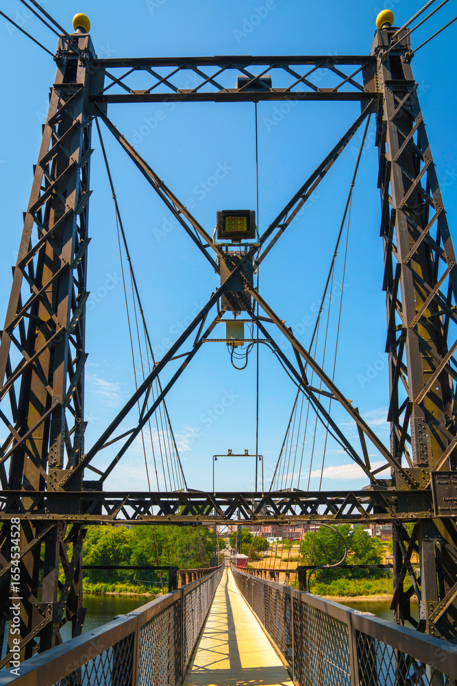 Fototapeta premium The Ticonic Footbridge, also known as the Two Cent Bridge, a historic 1903 suspension bridge over the Kennebec River, linking Waterville and Winslow in Kennebec County, Maine, USA