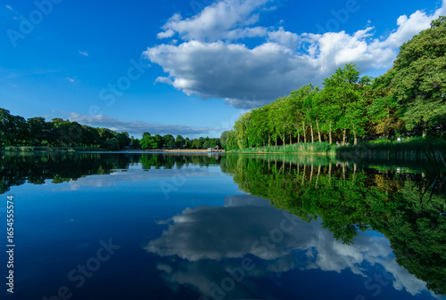 Obraz na plátne Orankesee in Berlin Alt-Hohenschönhausen with fluffy cumulus cloud and mirror-like water reflection on a sunny day