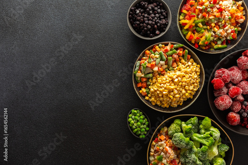 Fototapeta Naklejka Na Ścianę i Meble -  A variety of frozen vegetables and fruits arranged in plates, set against a dark background, capturing the essence of summer preservation for winter meals