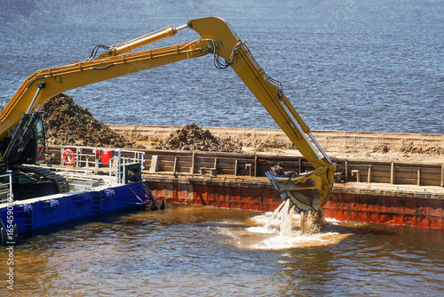 A specialized floating excavator cleans the bottom of the river from silt, sand and bottom sediments. Deepening of the navigable fairway.