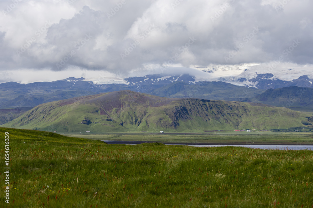 Obraz premium Green grass field with mountain view.