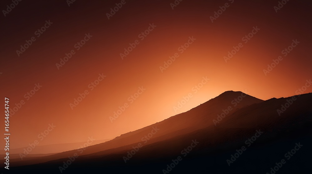 Obraz premium A silhouette volcanic ridge with glowing orange twilight sky above
