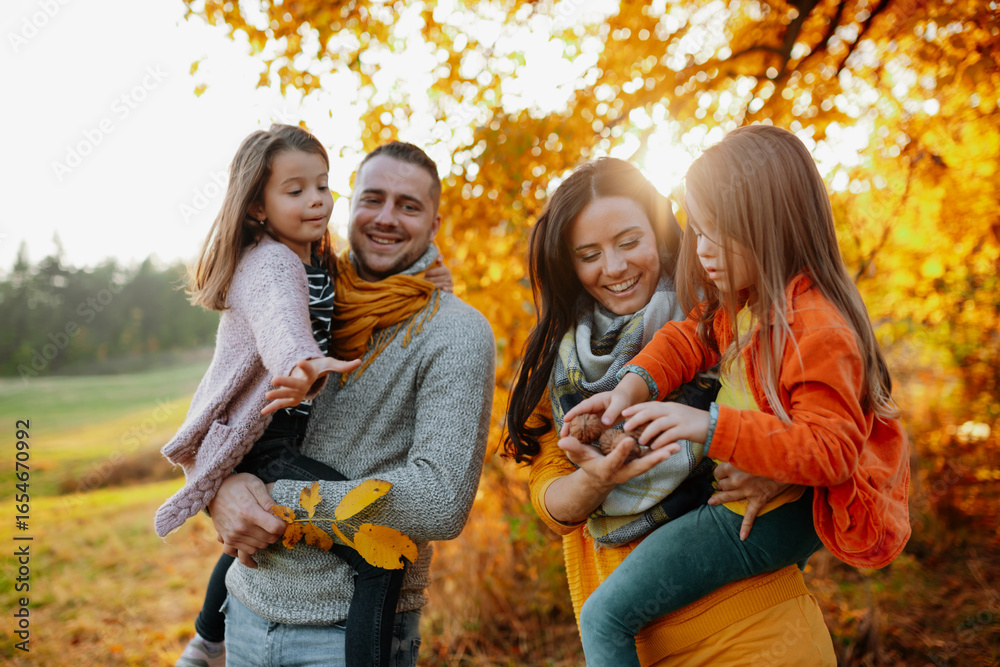 © Halfpoint - A portrait of young family with two small children in autumn nature at sunset.